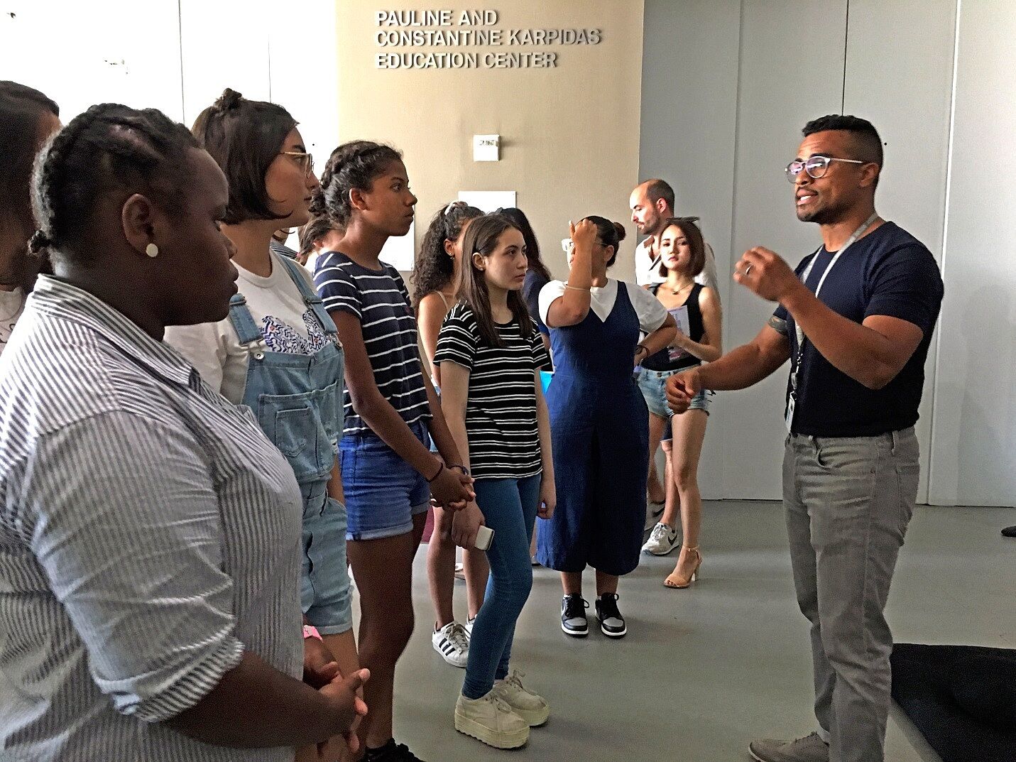 man explaining the museum exhibit to group of students