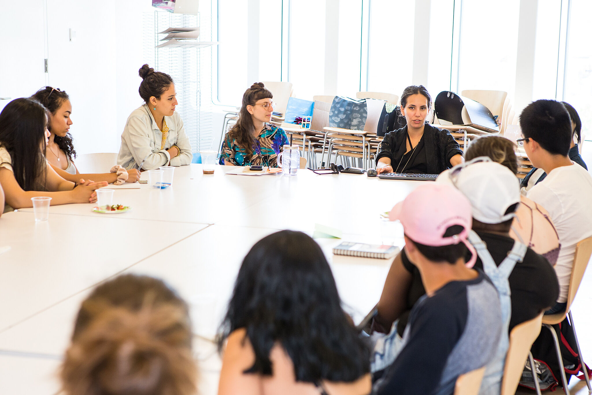 Students sit around table and talk with artist.