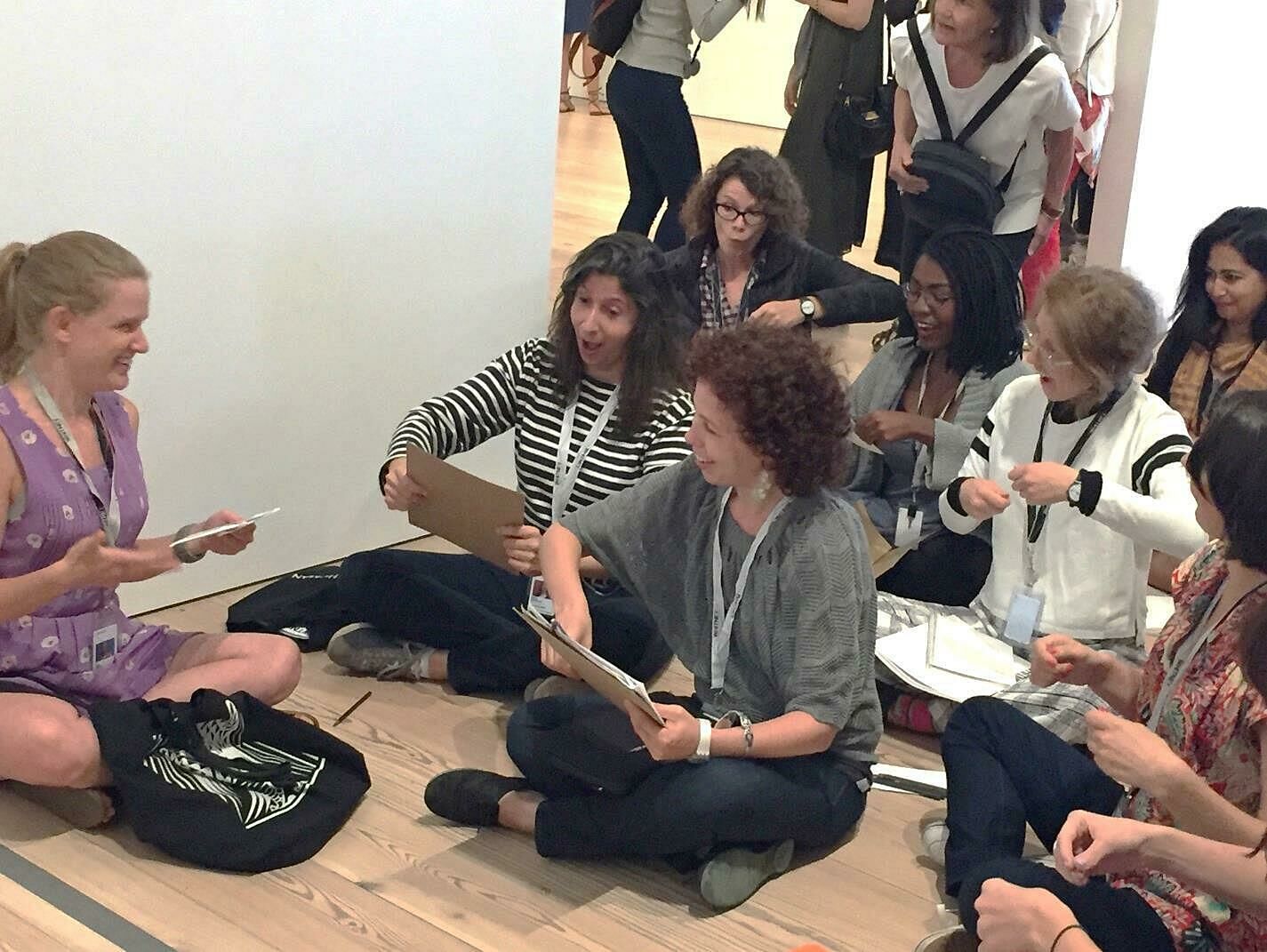 Teachers and museum staff sit on the gallery floor for an interactive event.