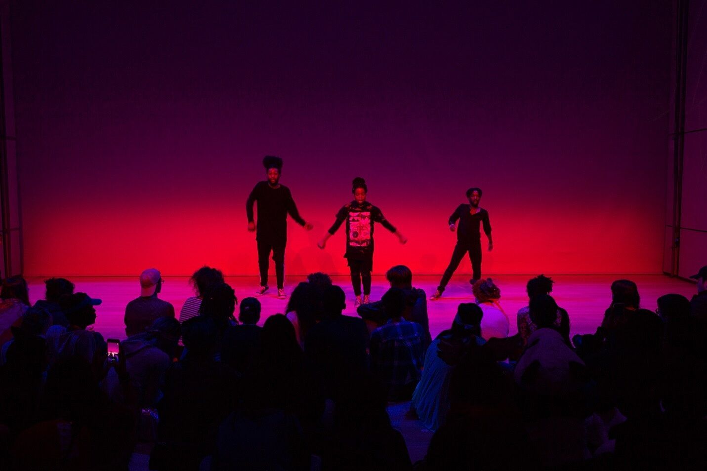 Three teens dance on stage during a museum event.