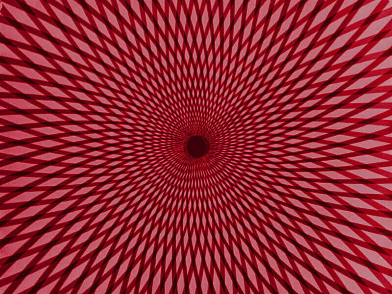 A still from a film by Oskar Fischinger. Concentric rings emanate from the center against a red ground