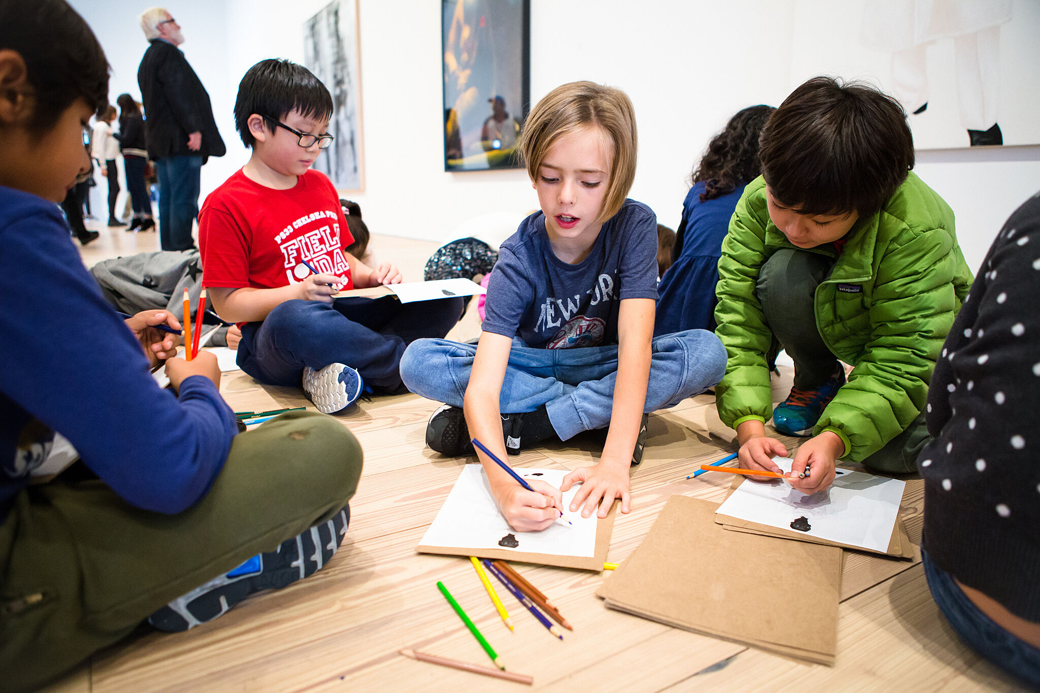 students sitting and drawing on paper