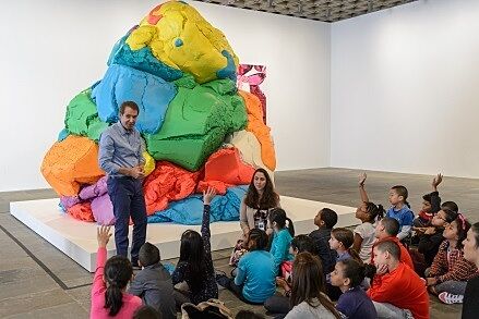 jeff koons in front of playdo sculpture with students