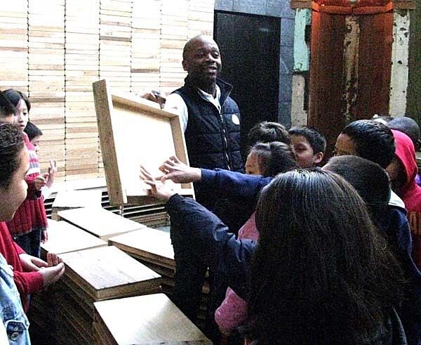 artist holding up frame with students pointing