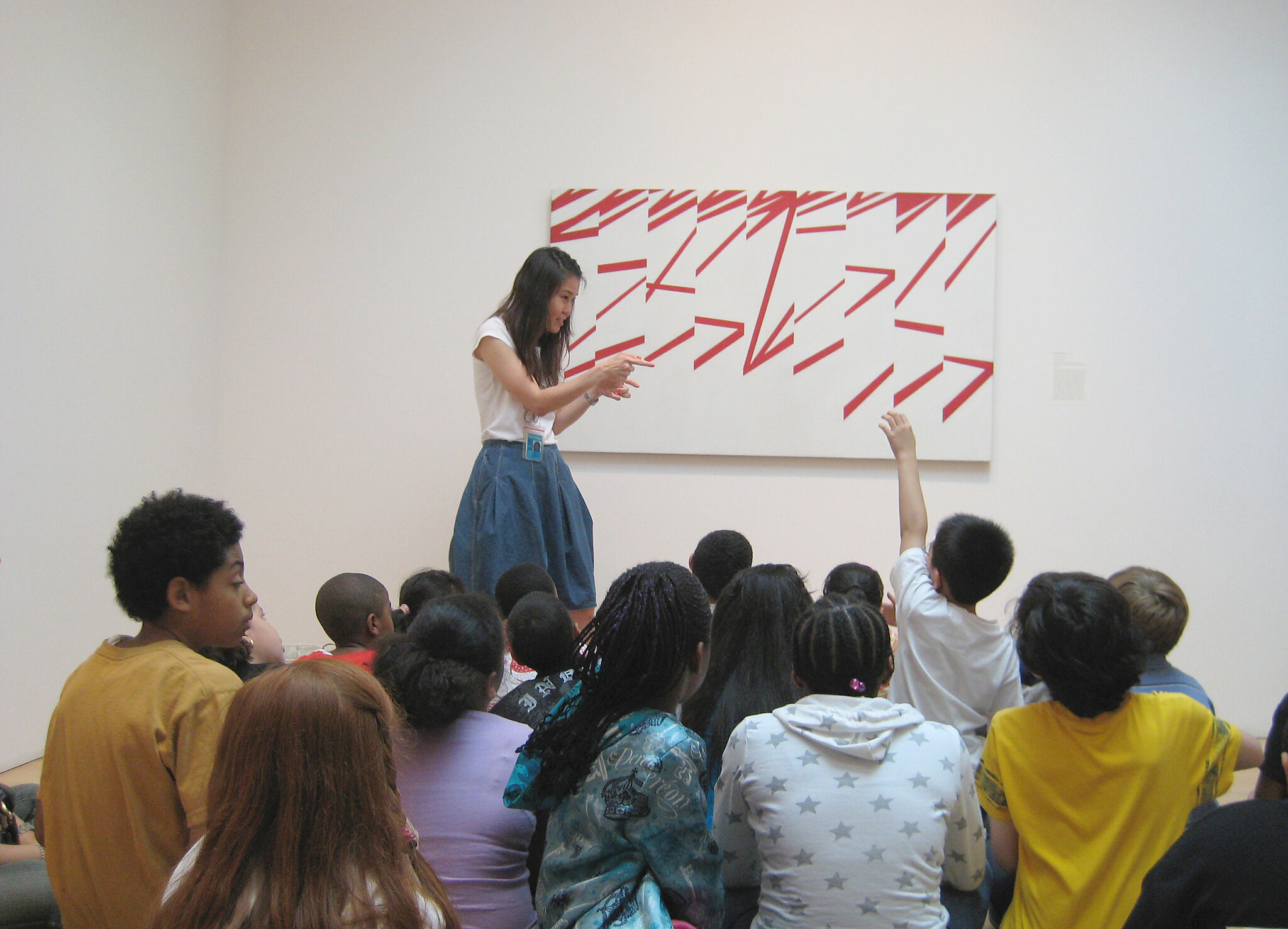 teacher in front of painting with group of sitting students