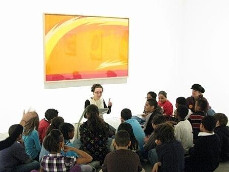 students sitting in front of painting and educator