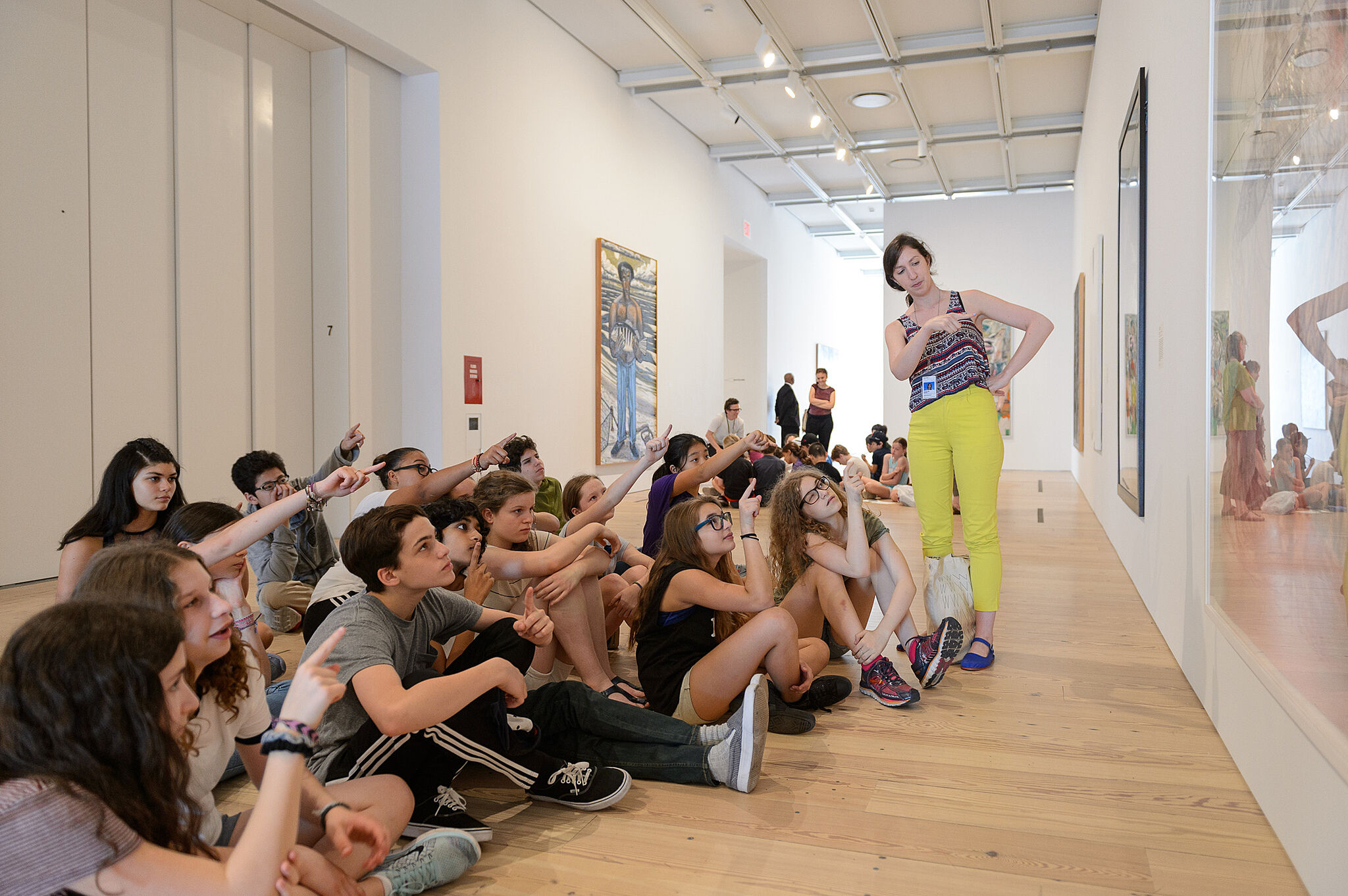 group of students sit and point at art in gallery