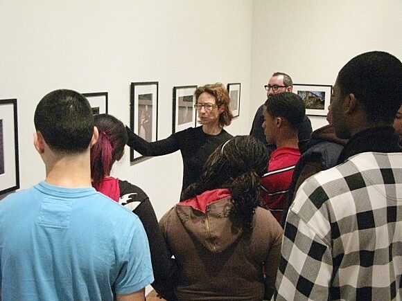 student talking to students about artwork on wall