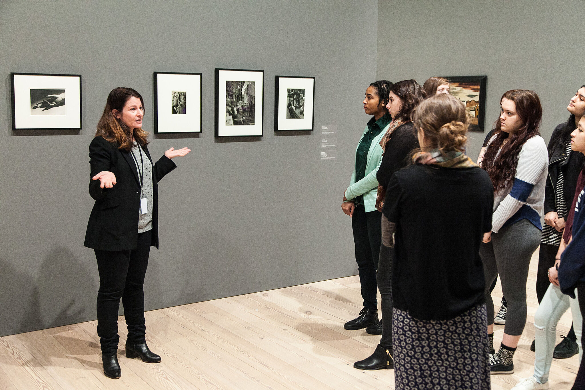 woman speaking to students in front of paintings