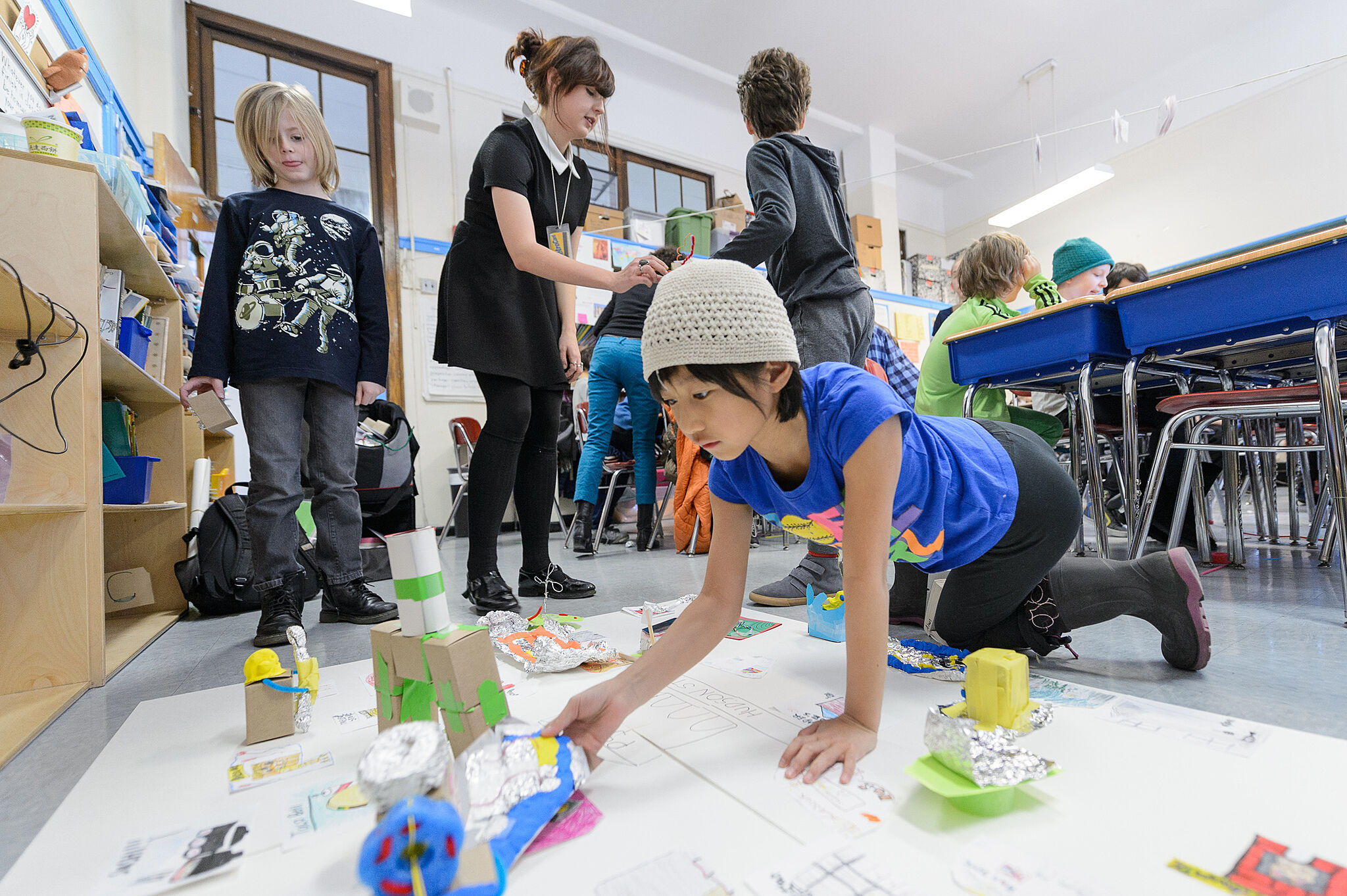 Student on ground arranging structures in a space.