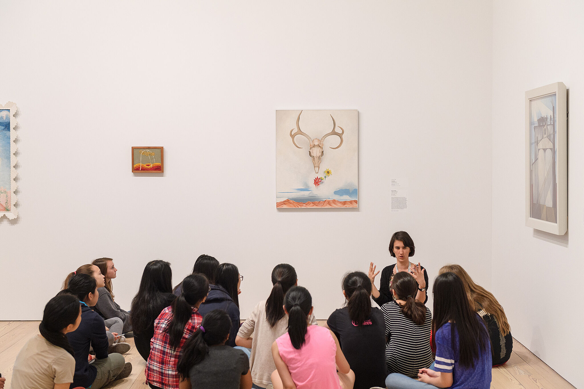 Students sitting and listening to teacher in gallery.