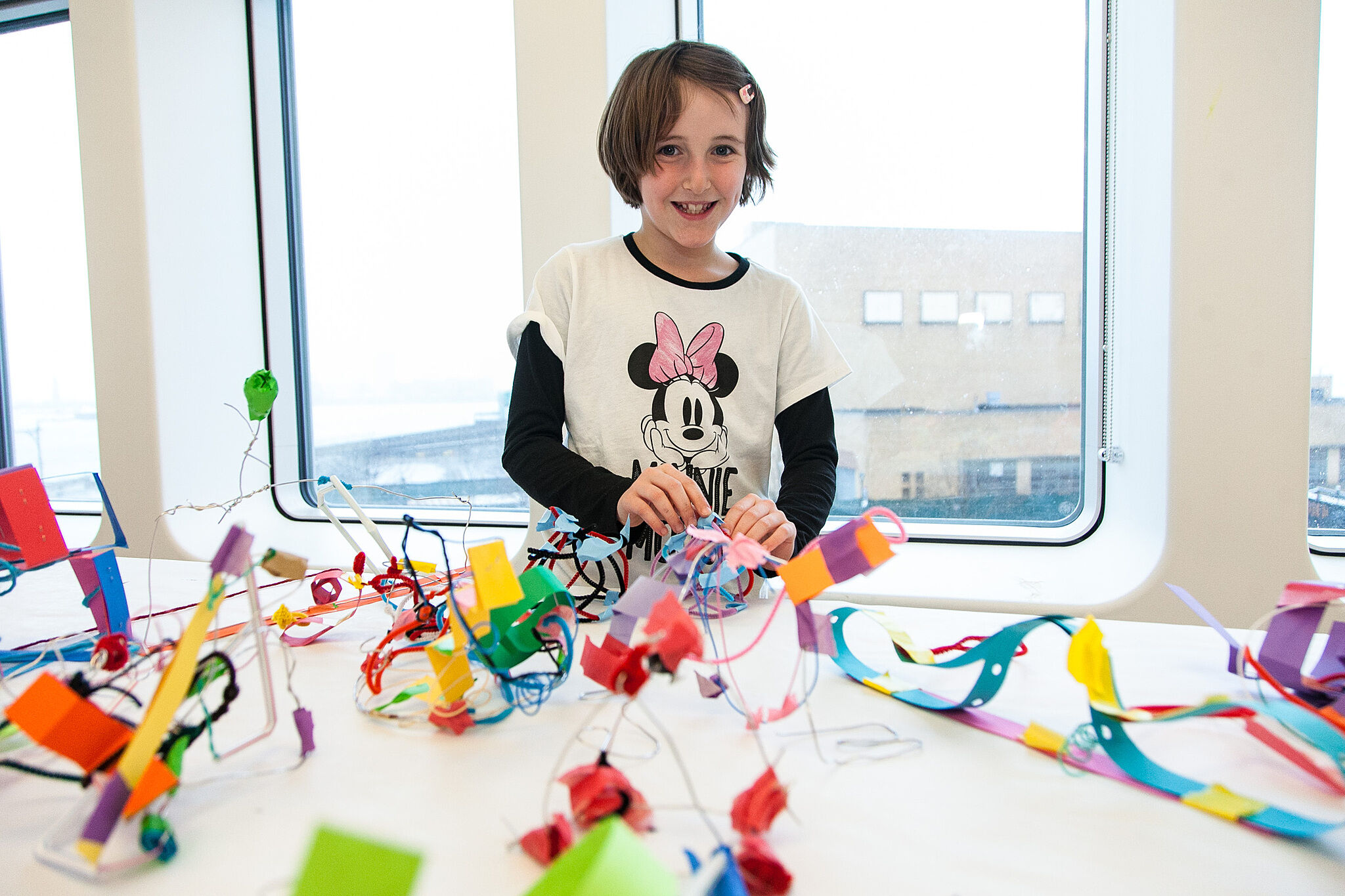 Child smiling in front of colorful crafts