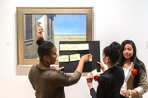 Students holding board in front of painting.