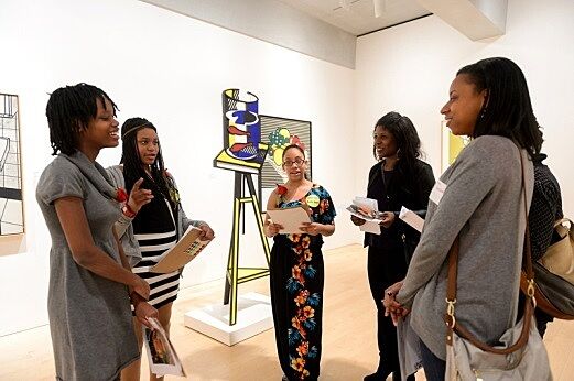 Students discussing artwork with parents in gallery.