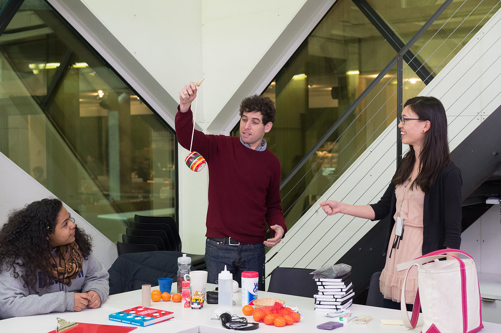 The artist demonstrates an object in front of two teens.