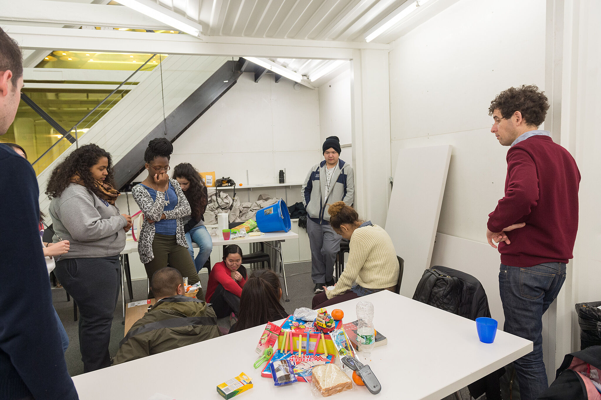 The artist works with students on a project with random objects.