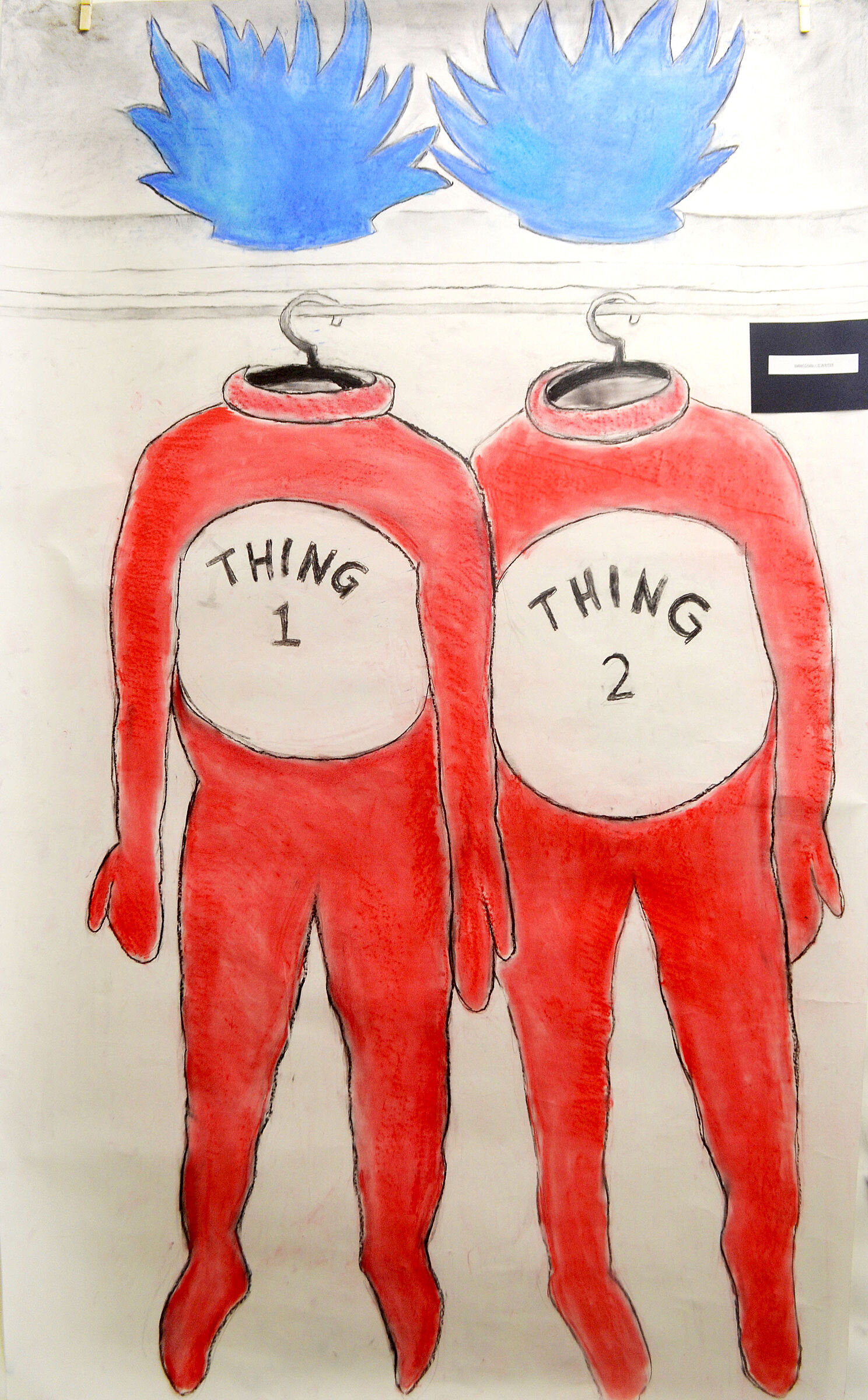 Two red costumes labeled "Thing 1" and "Thing 2" hang on a rack, with blue spiky wigs above them.