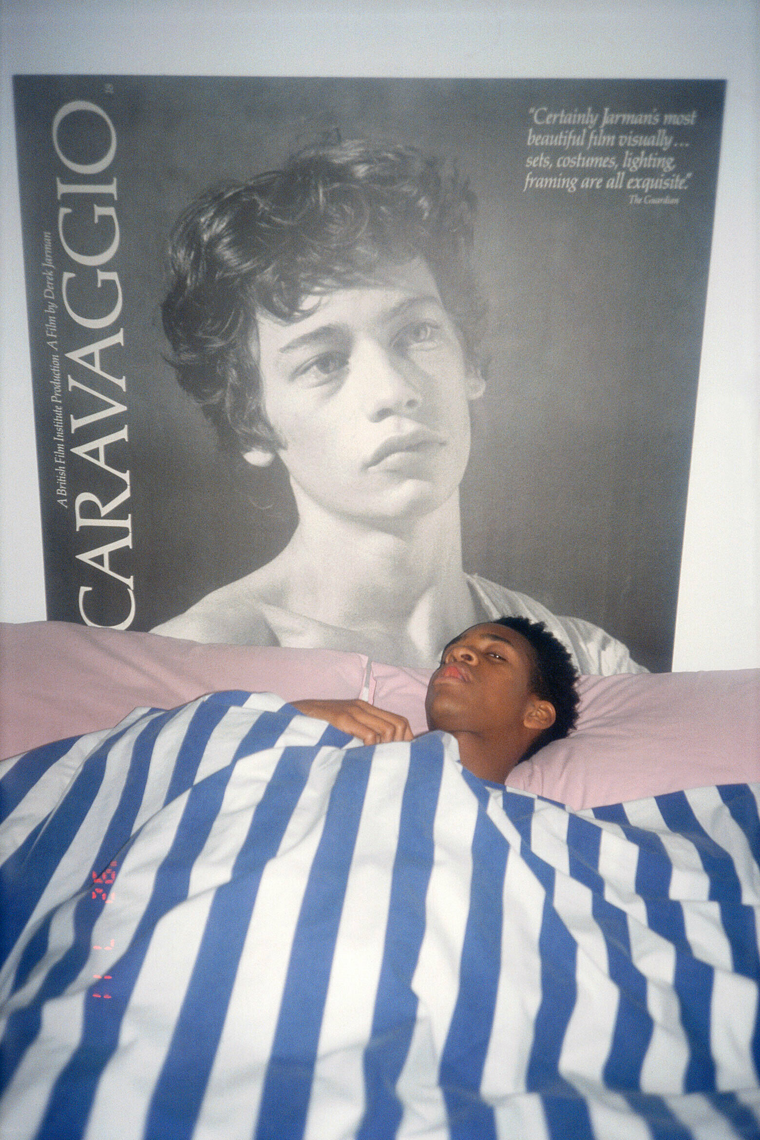 Photograph of Harris in bed with Caravaggio poster in background