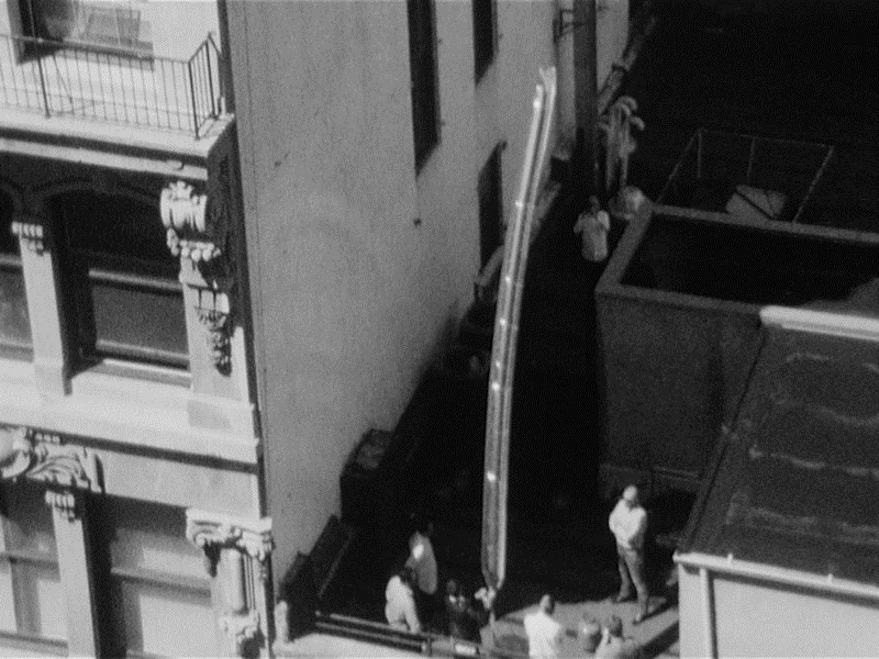 Black and white photo of people on building.