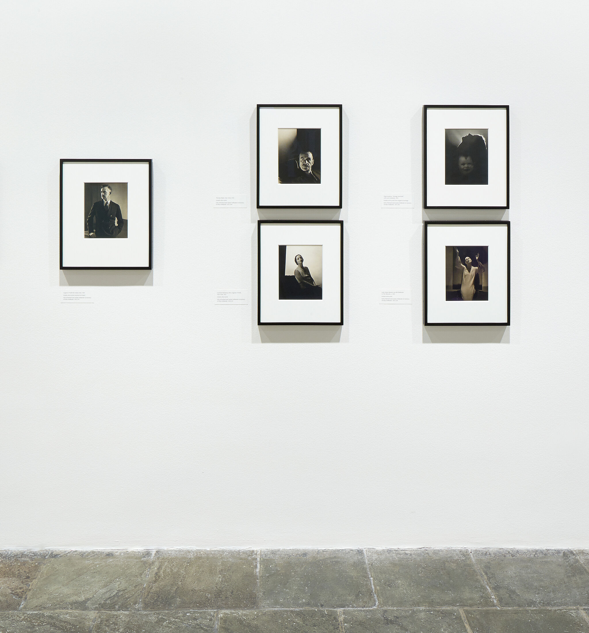 Five framed photographs on a gallery wall.