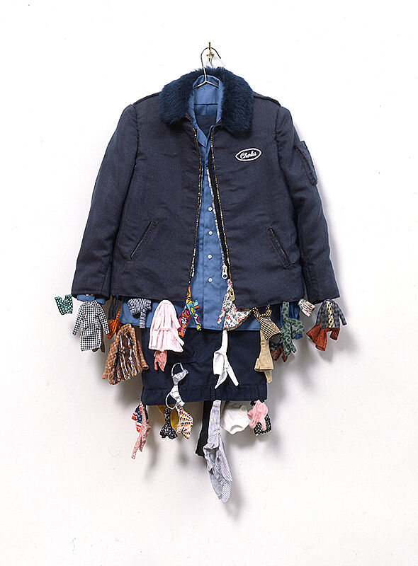 A workman's uniform with tiny clothing hanging off of it.