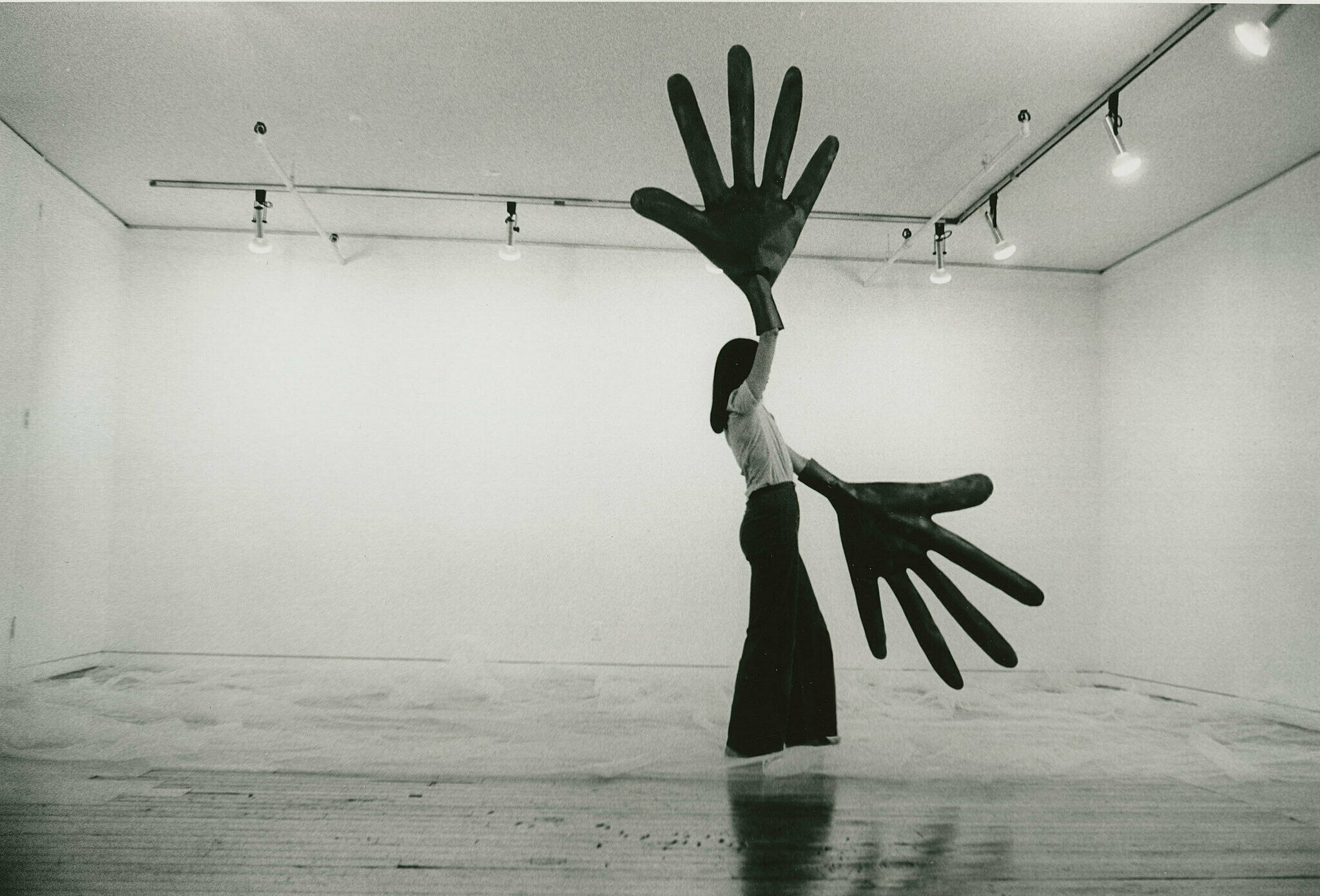 A woman standing in a gallery with giant hands.