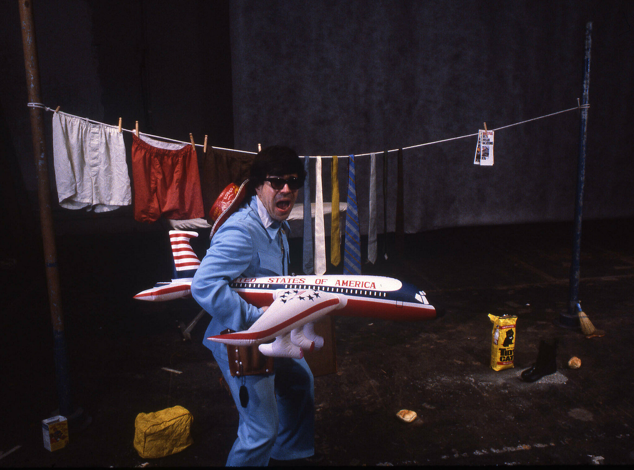 A man in a blue outfit holds a model airplane. 