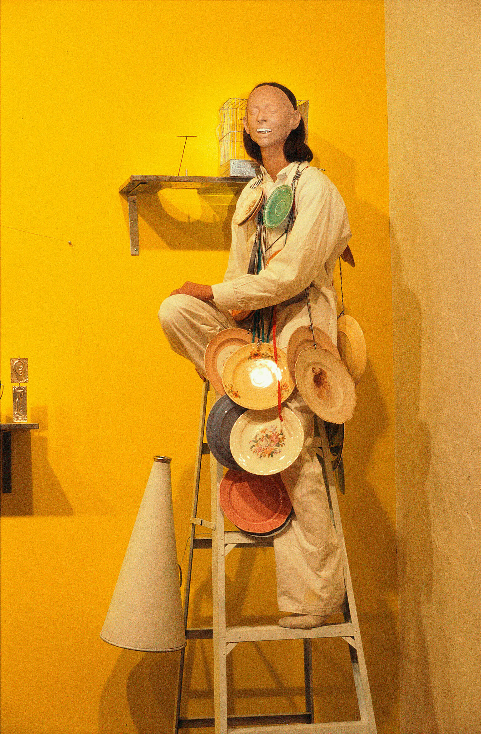 A performance artists stands on a ladder with plates attached to them.