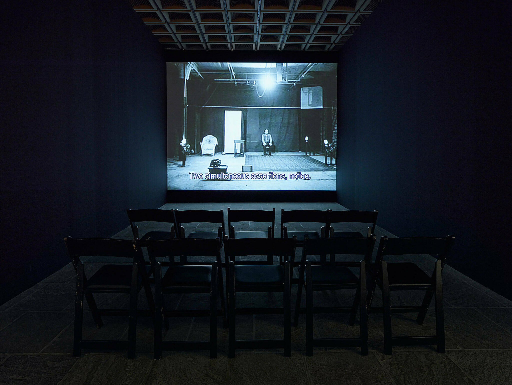 Video projection in a room with folding chairs.