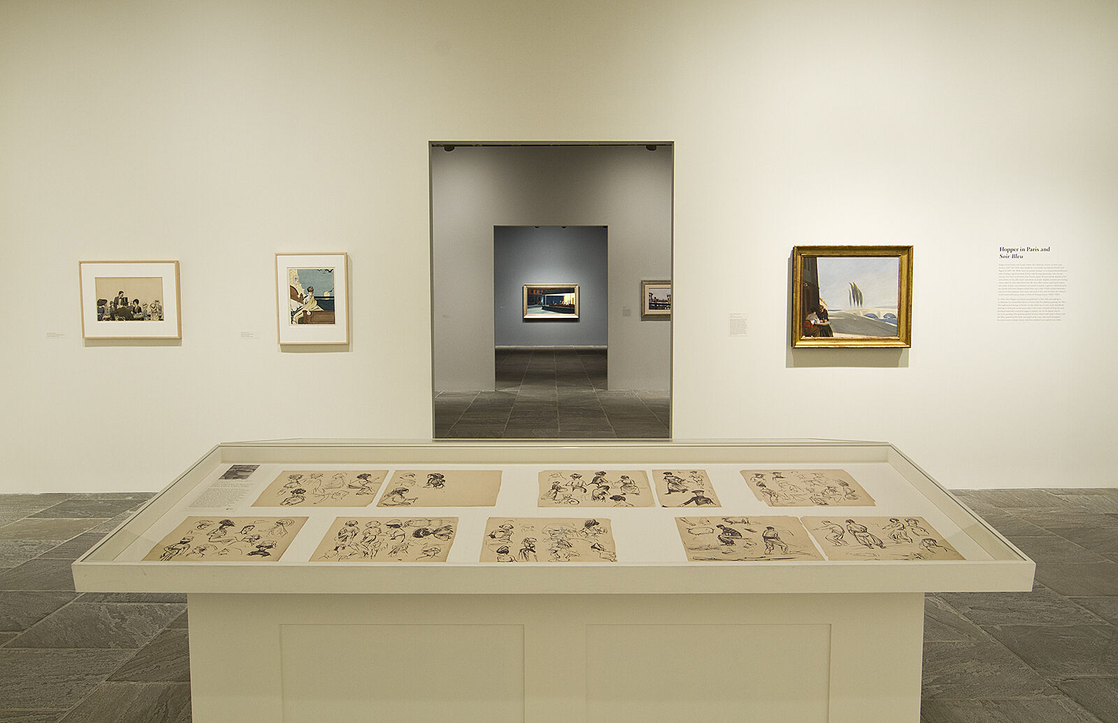 Sketches displayed in cases with paintings just beyond them.