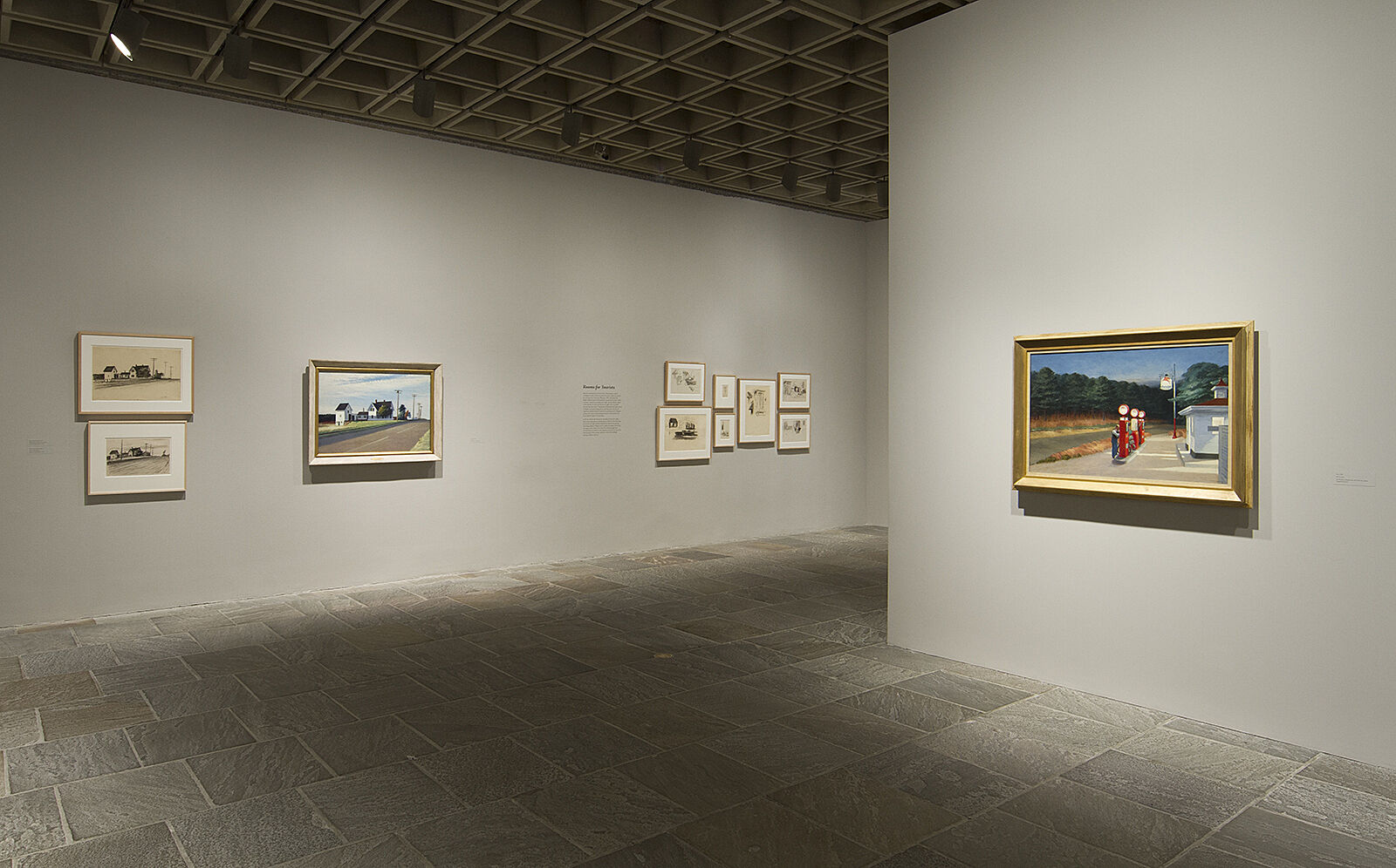 Paintings and drawings hang on the exhibition wall.