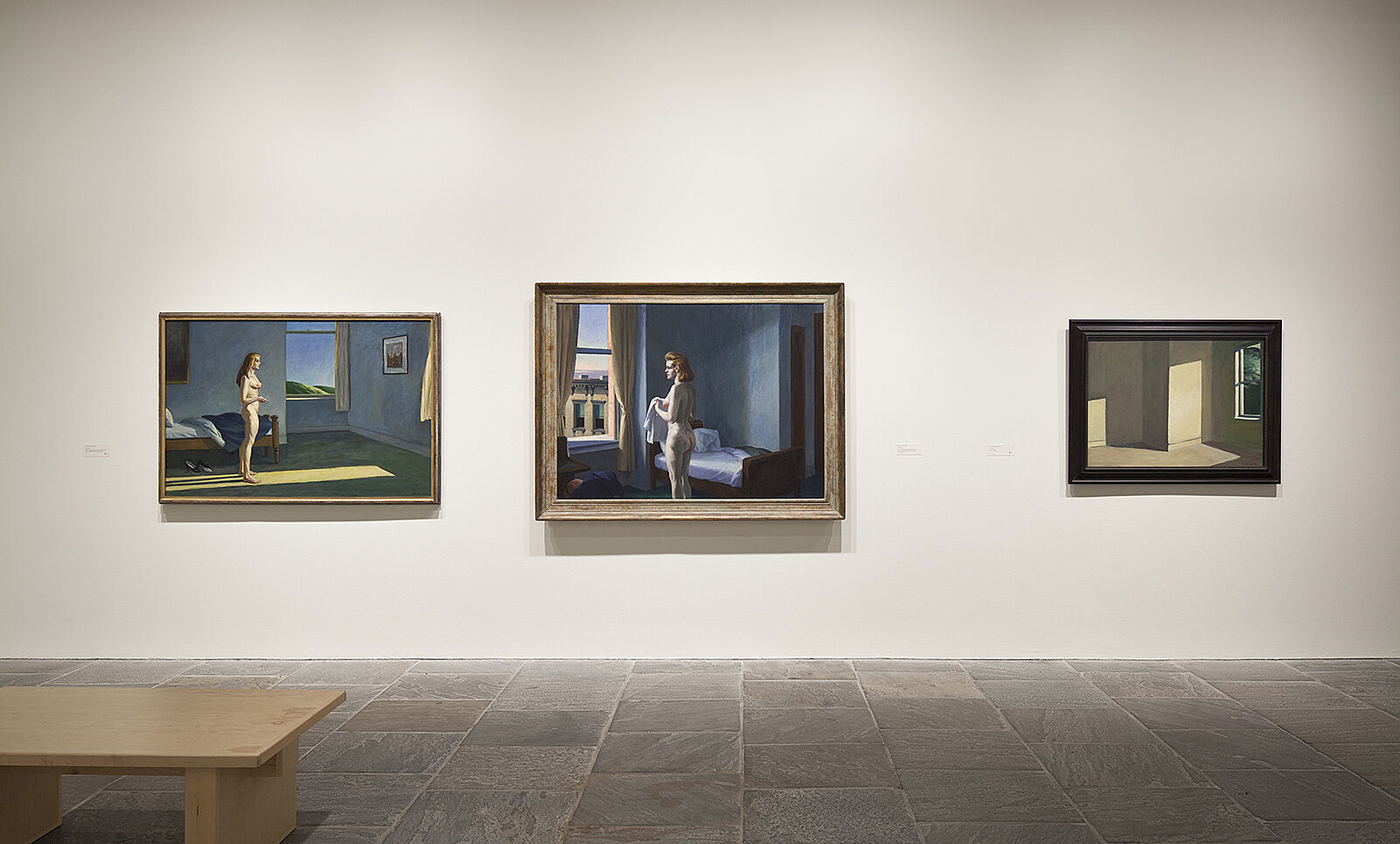 Three paintings hang beside each other in exhibition.
