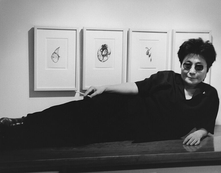 Yoko Ono reclining in front of artwork.