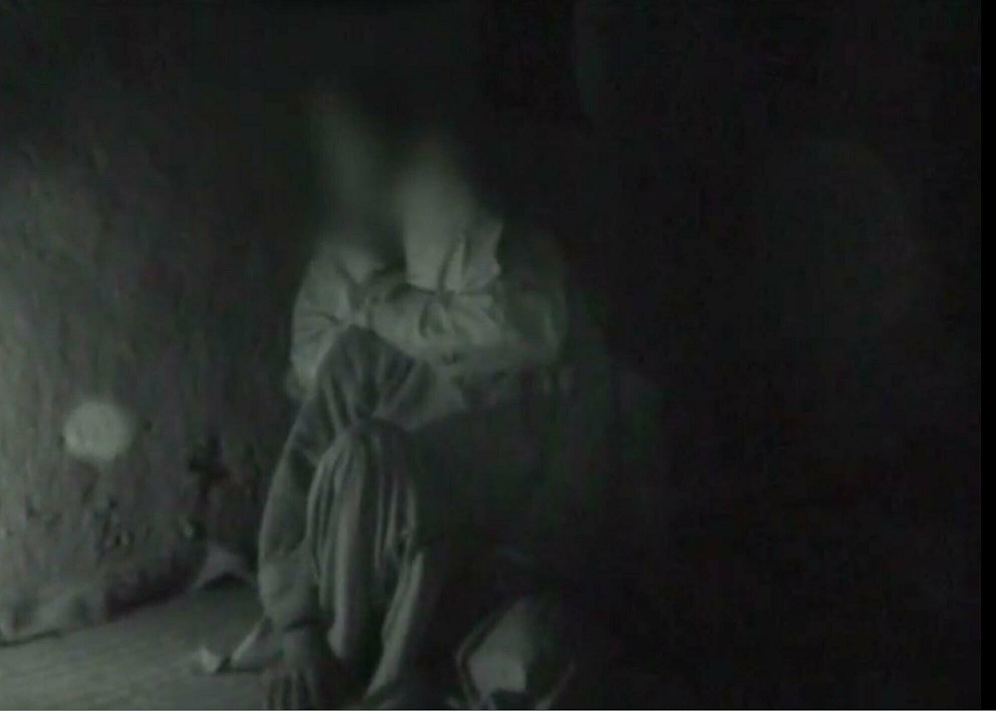 Blurry and dark image of a person sitting.