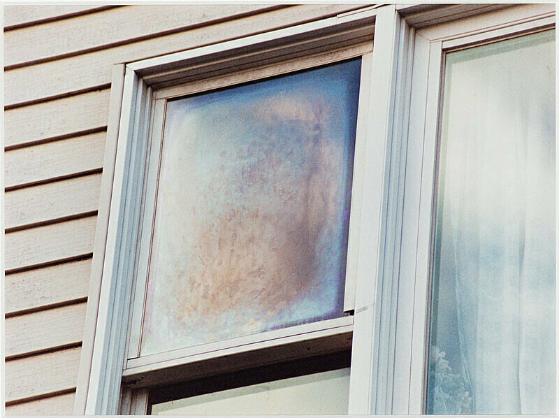 Window of a house with shades of blue and pink in it.