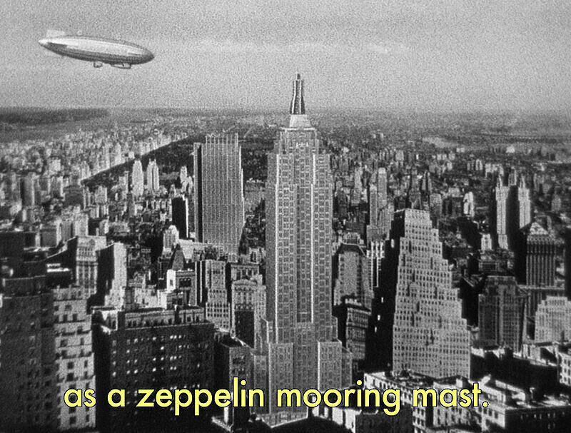 Black and white still of a Zeppelin flying over Manhattan.