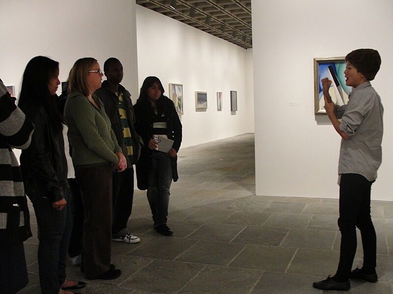 Artist talks to group of teens in gallery.