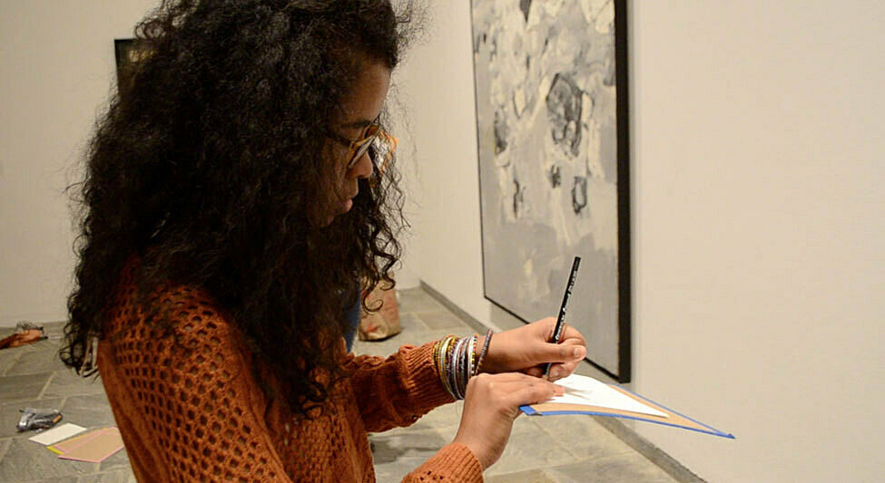 A student draws on paper in the gallery.