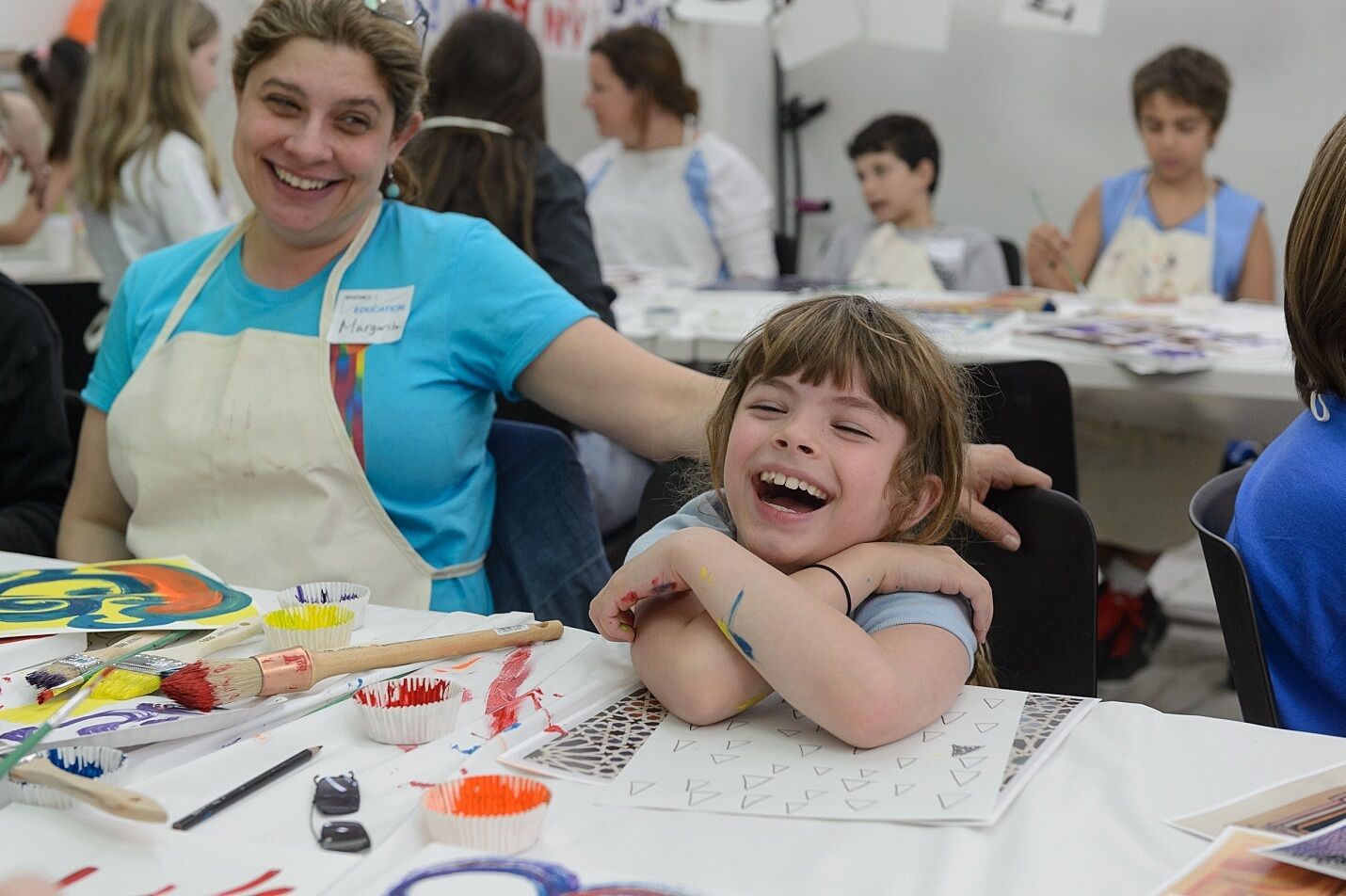 A mother and child laugh during an art class.