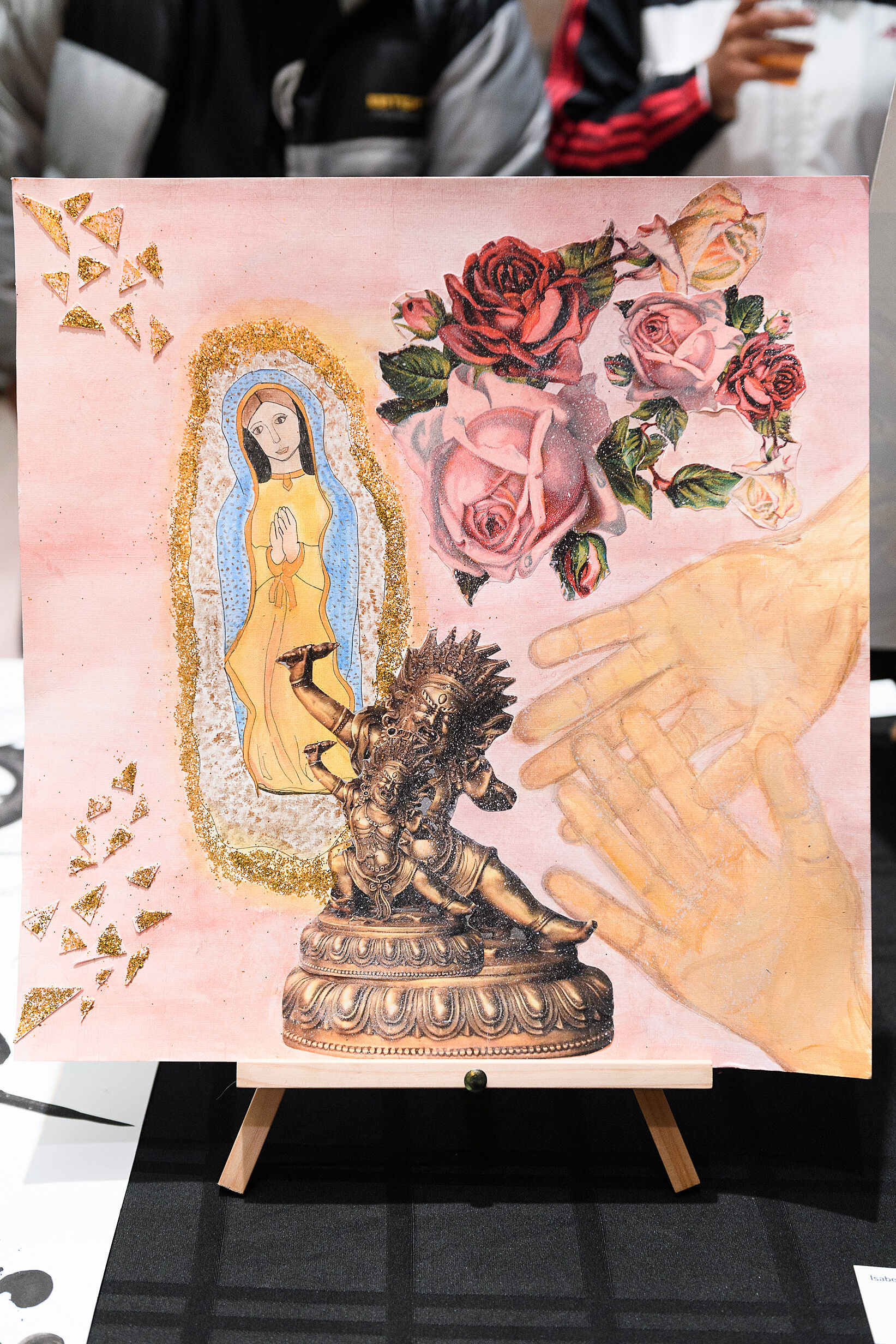 Hands, flowers, virgin mary and gold sparkles on a painting.