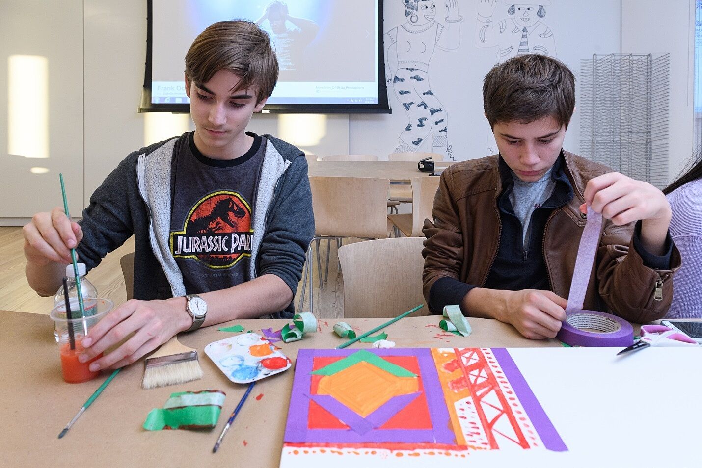 Two students mix paint and work on a collaborative art project.