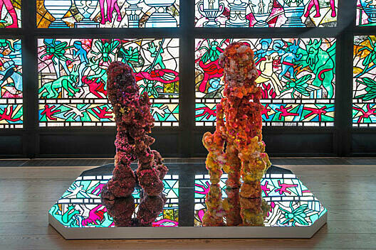 An installation view of a work by Raul de Nieves. Beaded shoes in front of a stained glass window