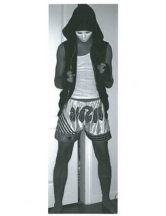 A teen artist wears a white mask and silver shorts.