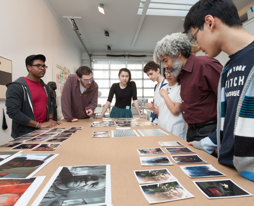 Fred Wilson talking to students over a table of artwork.