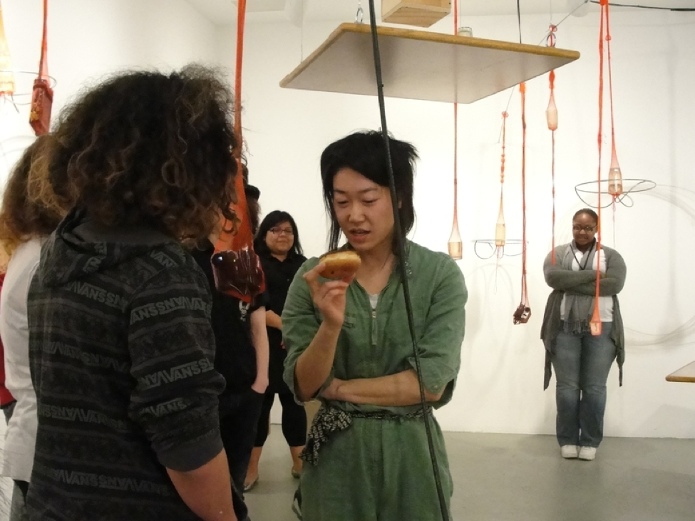 Artist Aki Sasamoto talks to students in a gallery.