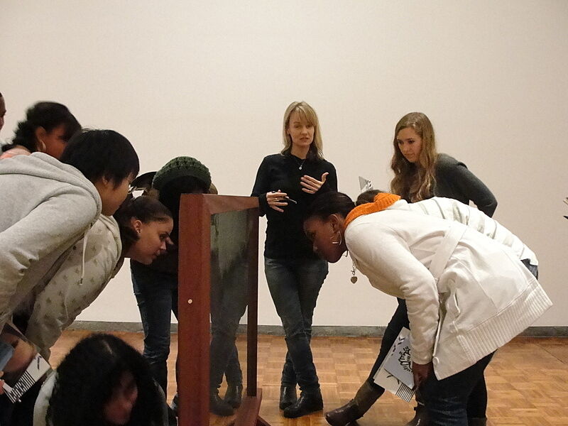 Suzanne Bennett looks at a sculpture with students. 