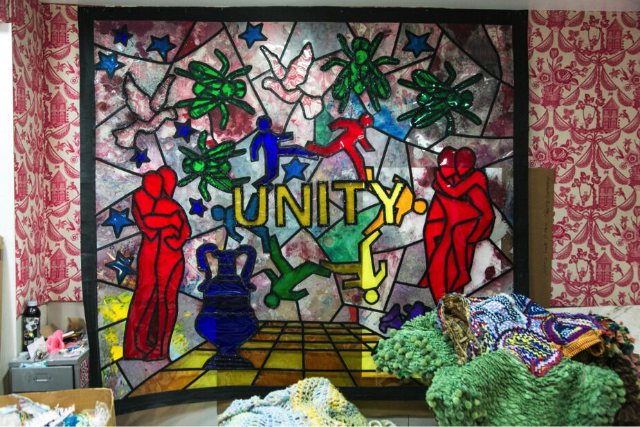 Stained glass art with the word "UNITY" surrounded by colorful figures, stars, insects, and abstract shapes.