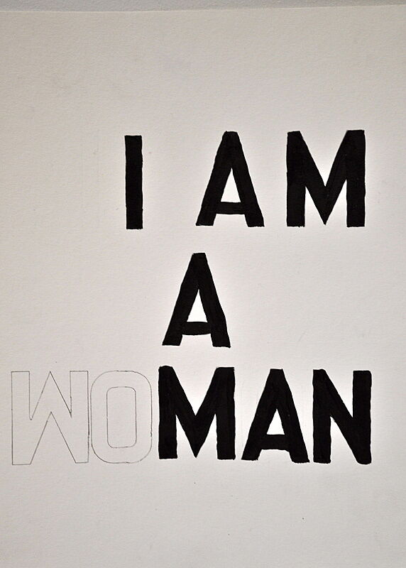 Black text on white background reads "I AM A WOMAN".