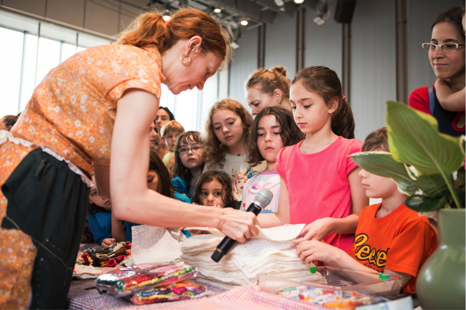 Susan Cianciolo showing a group of kids how to make placemats 