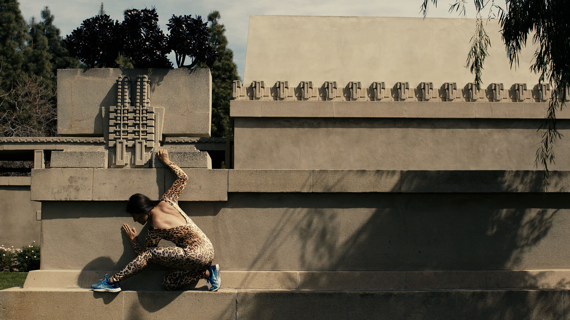 A woman in a leopard suit scaling a wall